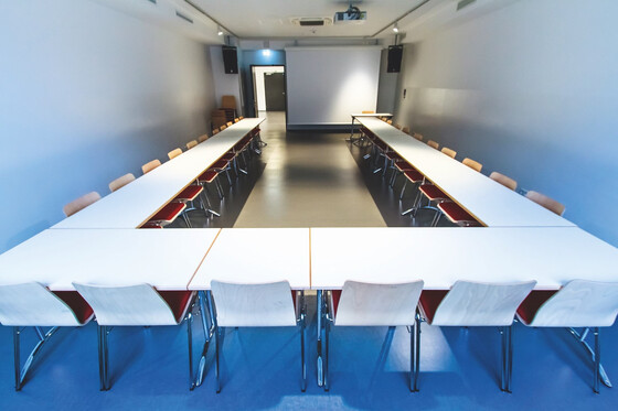 Ein großer Konferenzraum mit Tischen und Stühlen in U-Form. | © Name