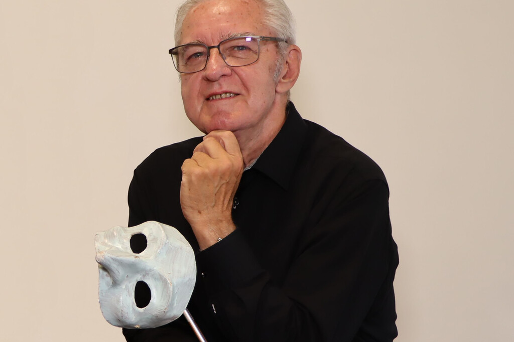 Hans Driesel lächelt nachdenklich neben einer kunstvollen Maske. | © Carolin Christoph