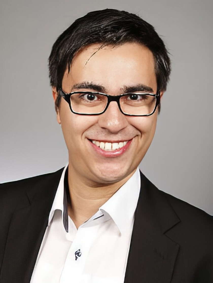 Jonathan Armas lächelt freundlich in einem schwarzen Anzug und einer weißen Bluse.
